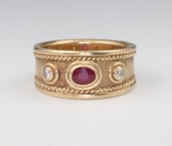 A 9ct yellow gold Etruscan style ring set with an oval cut ruby and 2 brilliant cut diamonds, the