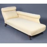 An Edwardian mahogany chaise longue upholstered in pale yellow material raised on turned supports