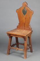 A 19th Century pitch pine hall chair, the shaped solid back with shield and monogram to the centre