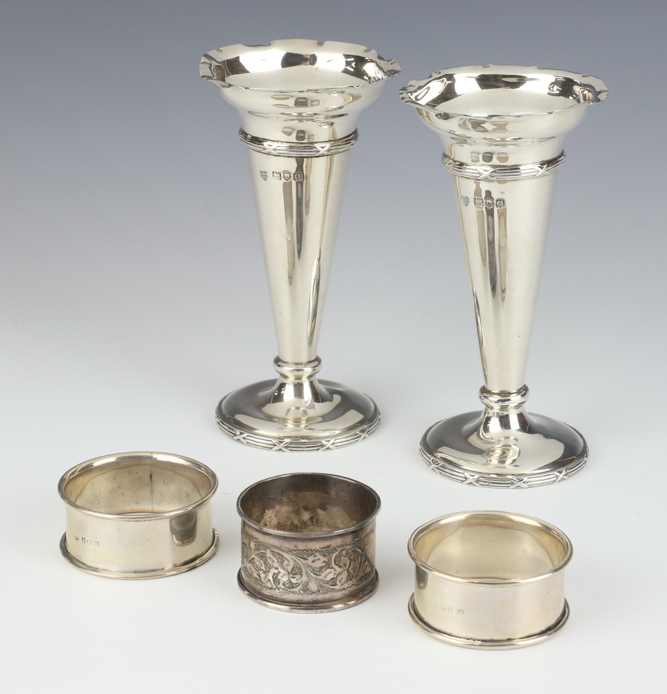 A pair of Edwardian tapered silver posy vases, London 1909, 13cm and 3 silver napkin rings, 256