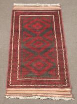 A red and black ground Belouche rug with 3 diamond shaped medallions to the centre within a multi