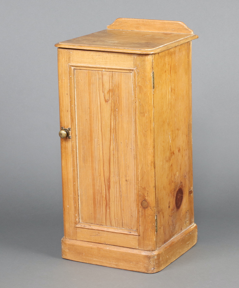 A Victorian pine pot cupboard with raised back, fitted a shelf enclosed by panelled door, on a