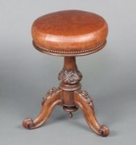 A Victorian carved rosewood piano stool, the seat upholstered in brown leather, raised on a carved