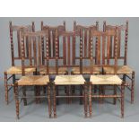 A set of 7 Art Nouveau oak stick and rail back dining chairs with woven rush seats, raised on bobbin