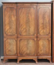 A Georgian style mahogany triple breakfront wardrobe with moulded cornice having Grecian key