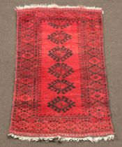 A red and black ground Afghan rug with 5 octagons to the centre 143cm x 84cm