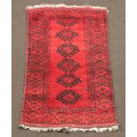 A red and black ground Afghan rug with 5 octagons to the centre 143cm x 84cm