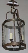 A circular wrought iron and glass hall lantern 41cm h x 21cm diam. This lot has not been tested