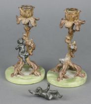 A pair of gilt metal candlesticks in the form of tree stumps with bacchanalian figure raised on