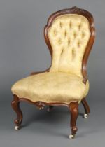 A Victorian carved mahogany show frame nursing chair upholstered in buttoned yellow material, seat