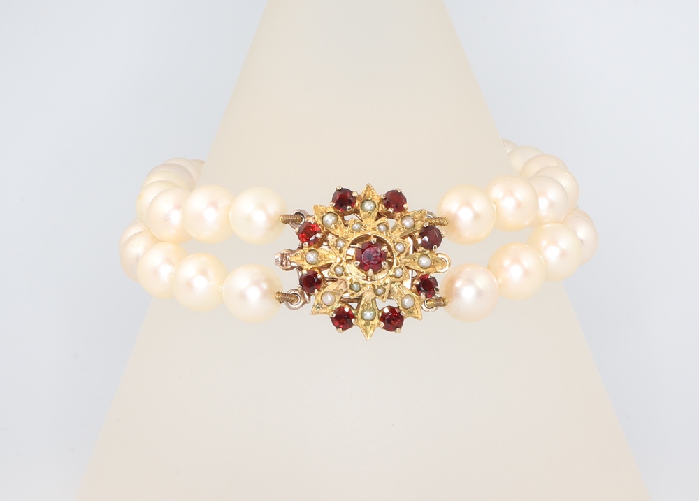 A yellow metal 9ct double strand pearl bracelet with garnet and seed pearl clasp 18cm