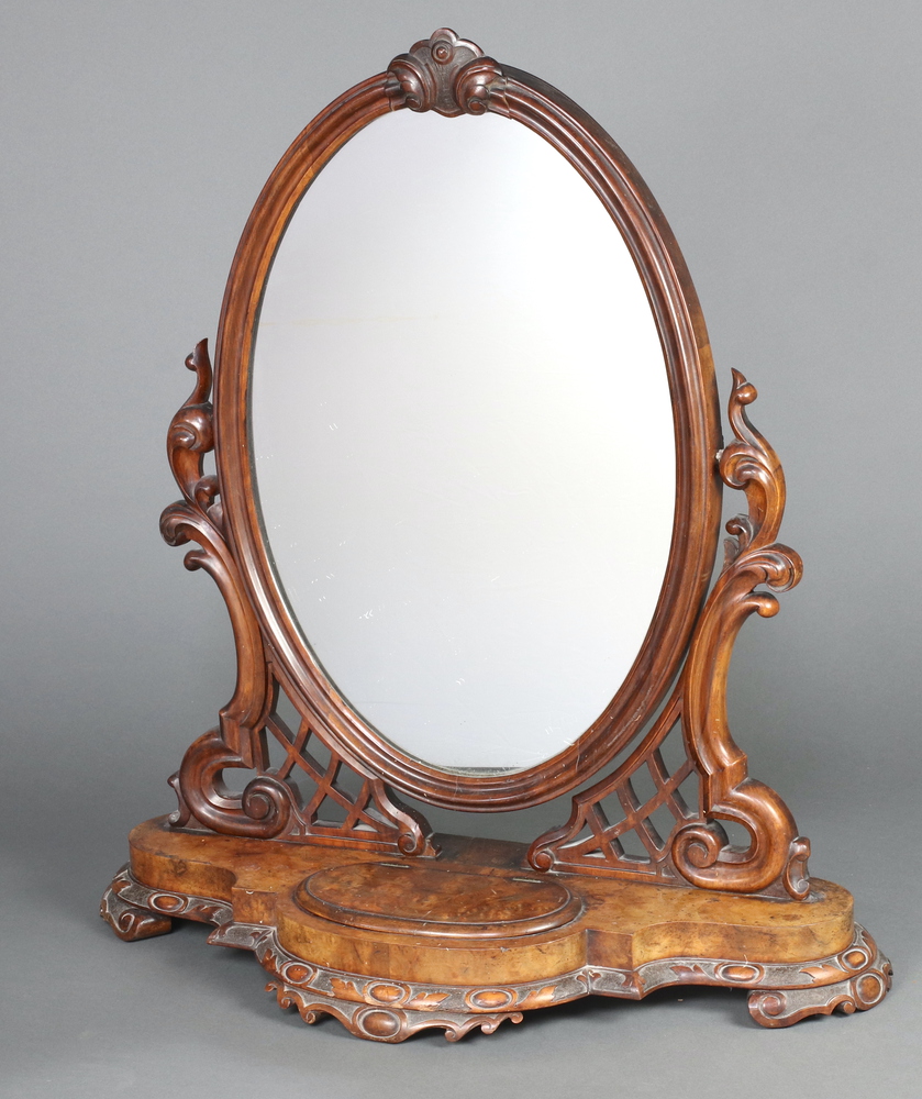 A Victorian oval plate dressing table mirror contained in a carved and pierced stand, the shaped