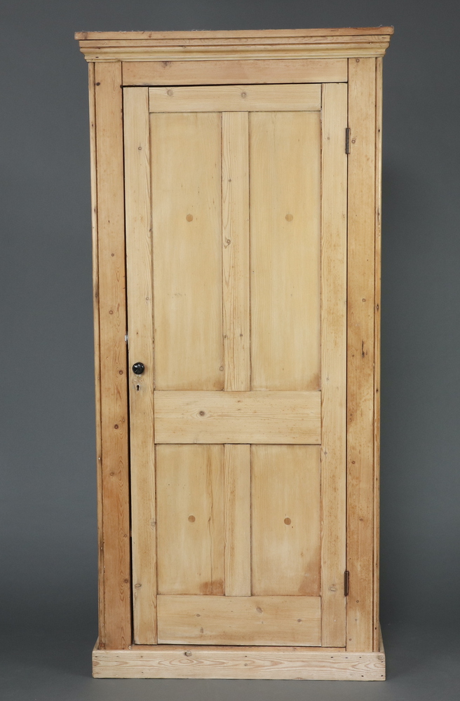A Victorian pine wardrobe with moulded cornice, fitted a shelf and hanging space above a recess,