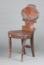 A Georgian mahogany carved hall chair with oval shaped back and seat, raised on turned and fluted