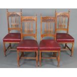 A set of 4 Art Nouveau oak stick and rail back dining chairs, the seats upholstered in red