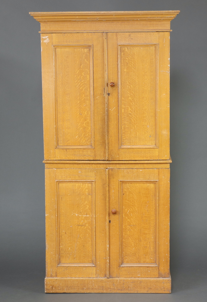 A Victorian pine scumble painted press cabinet with moulded cornice, both sections fitted shelves