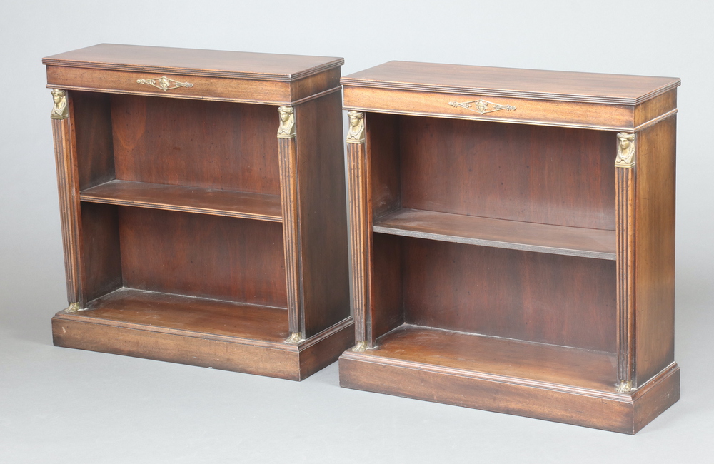 A pair of empire style mahogany bookcases fitted a shelf with sphinx capitals and fluted columns