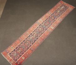 A red, blue and white ground Caucasian style runner with central floral medallion contained within a