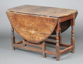 An 18th Century oak oval drop flap gate leg dining table fitted a drawer raised on turned and