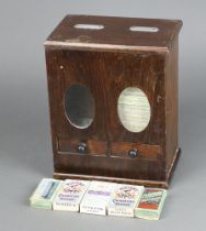 A 1920's table top cigarette vending machine contained in an oak case, the base fitted 2 drawers