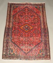 An orange, red and blue ground Persian rug with diamond medallion to the centre 173cm x 109cm Flecks