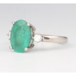 A platinum dress ring set an oval cut emerald supported by 2 diamonds, size O, gross weight 6.1g
