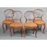 A set of 4 Victorian carved walnut balloon back dining chairs with carved mid rails, overstuffed