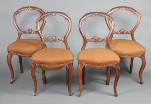 A set of 4 Victorian carved walnut balloon back dining chairs with carved mid rails, overstuffed