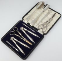 A cased set of silver plated grape scissors, 2 pairs of nut crackers and 2 nut picks, together
