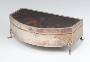An Art Deco silver and tortoiseshell bow front trinket box with hinged lid, raised on scrolled