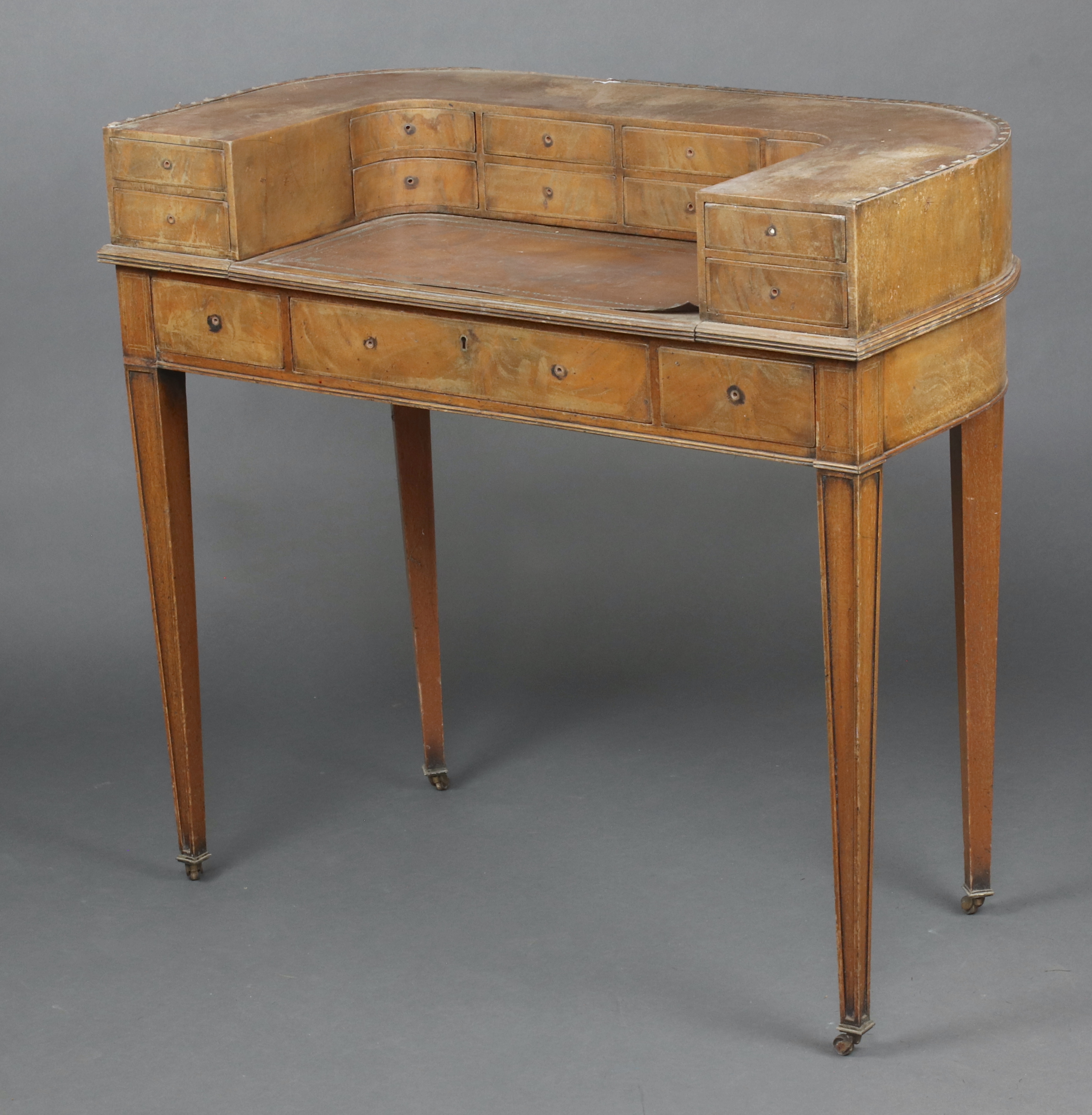 An Edwardian bleached mahogany Carlton House desk, the arched back fitted 12 drawers, the base