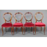 A set of 4 Victorian carved walnut balloon back dining chairs with over stuffed seats, raised on