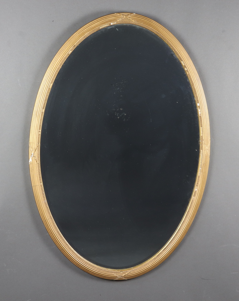 A 19th Century oval bevelled plate wall mirror contained a ribbon and reeded ball studded gilt frame