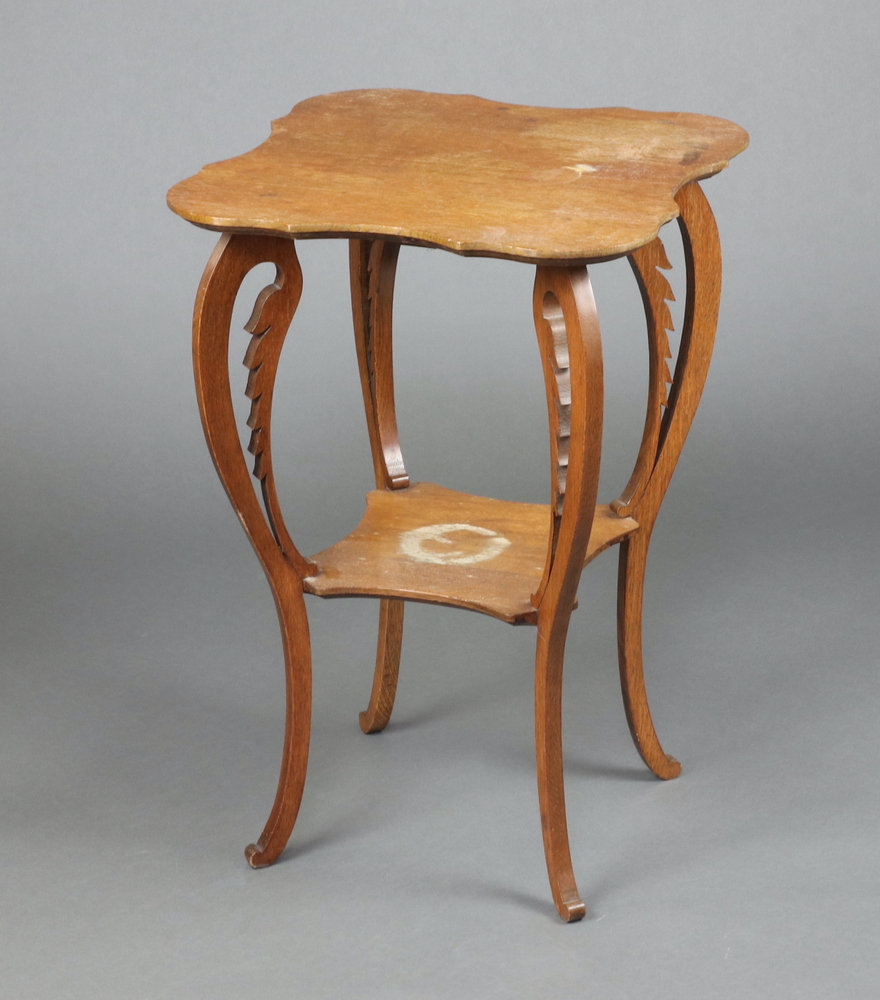 An Edwardian oak Liberty style 2 tier occasional table, raised on carved and pierced cabriole