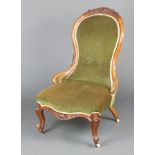 A Victorian carved walnut show frame nursing chair, the seat and back upholstered in green material,