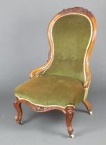 A Victorian carved walnut show frame nursing chair, the seat and back upholstered in green material,