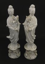 A pair of Chinese blanc de chine figures modelled as Guanyin holding a flower on a lotus base.