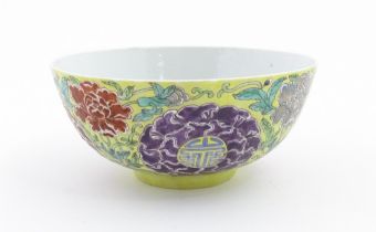 A Chinese famille jeune bowl decorated with flowers, foliage and auspicious symbols. Character marks