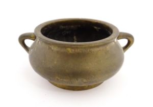 A Chinese cast bronze censer with twin handles. Character marks under. Approx. 2 1/4" high x 5 3/