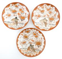 Three Japanese Kutani plates decorated with flowers, foliage and two birds, with foliate detail to