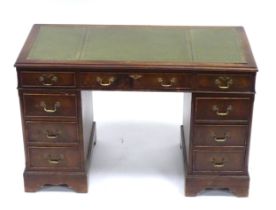 A 20thC mahogany pedestal desk with nine drawers, the top with green tooled leather insert, the