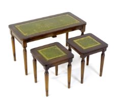 A nest of three tables with gold tooled green leather tops. The largest measuring 30" wide x 14 1/2"