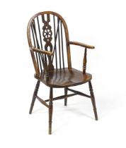 An early 20thC wheel back Windsor chair, having a shaped seat and raised on turned tapering legs