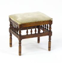 An Aesthetic Movement footstool, the upholstered seat above a gallery with turned supports and