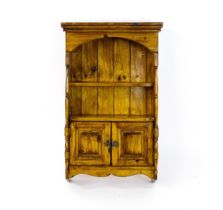 A small wall hanging cabinet of pine construction, with a moulded cornice above two shelves and