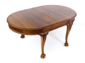 A mahogany dining table with an oval, gadrooned table top above four large cabriole legs with
