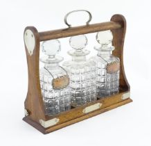 A late 19th / early 20thC oak tantalus with silver plate mounts, containing three glass decanters