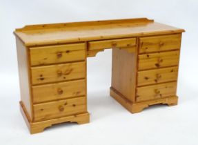 A pine double pedestal desk with a moulded top and a shaped upstand, having two banks of four