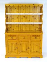 A pine dresser with a three tier plate rack above three short drawers and three panelled cupboards