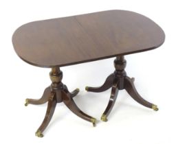 A Regency style double pedestal mahogany dining table with a reeded edge and an additional leaf.